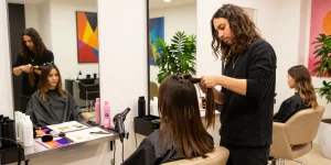 Hair style trend transformation with stylist applying extensions in a vibrant salon.